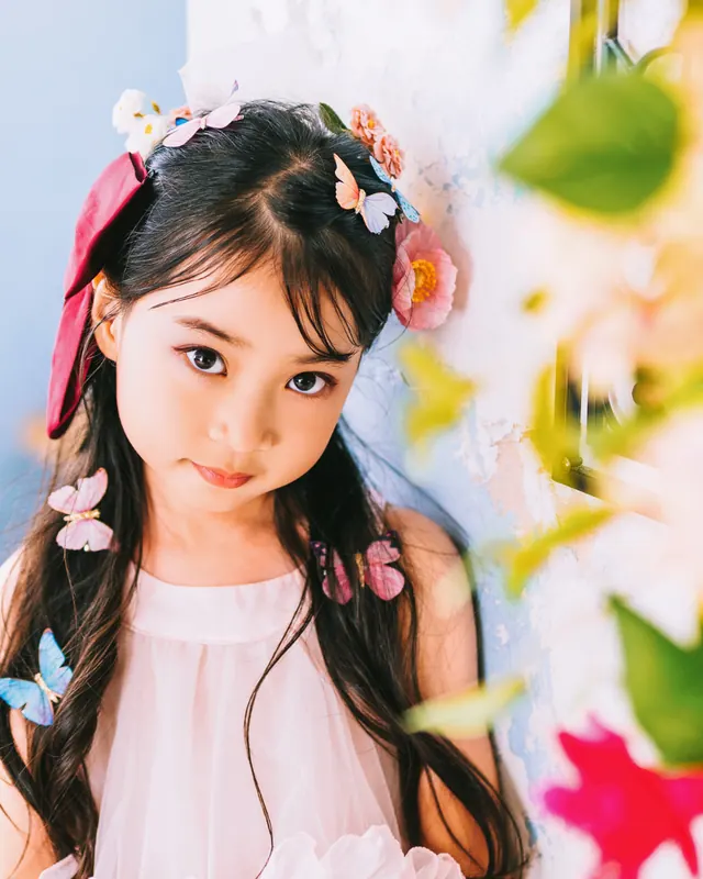 おろした髪に蝶と花の髪飾りを散らした、ピンクのドレスの女の子