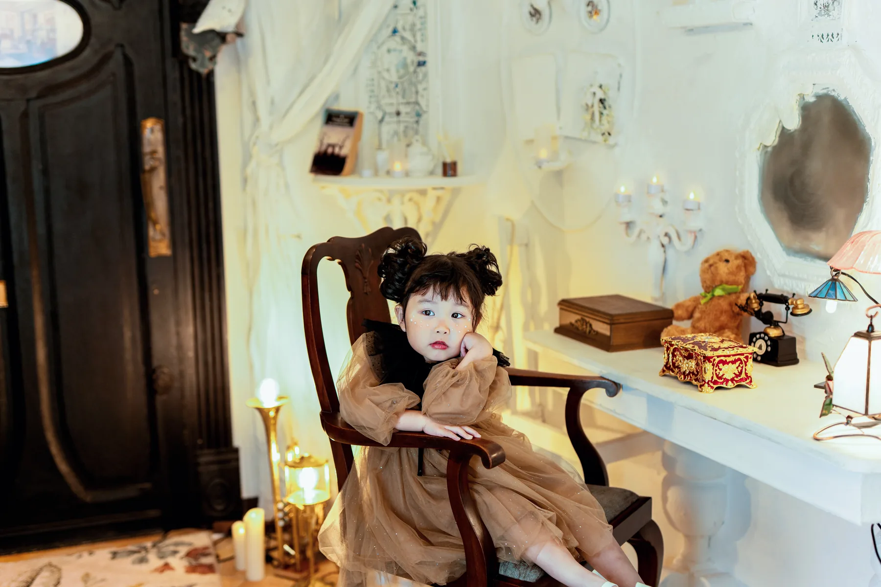白い机の部屋で椅子に座る、茶色のワンピースの女の子