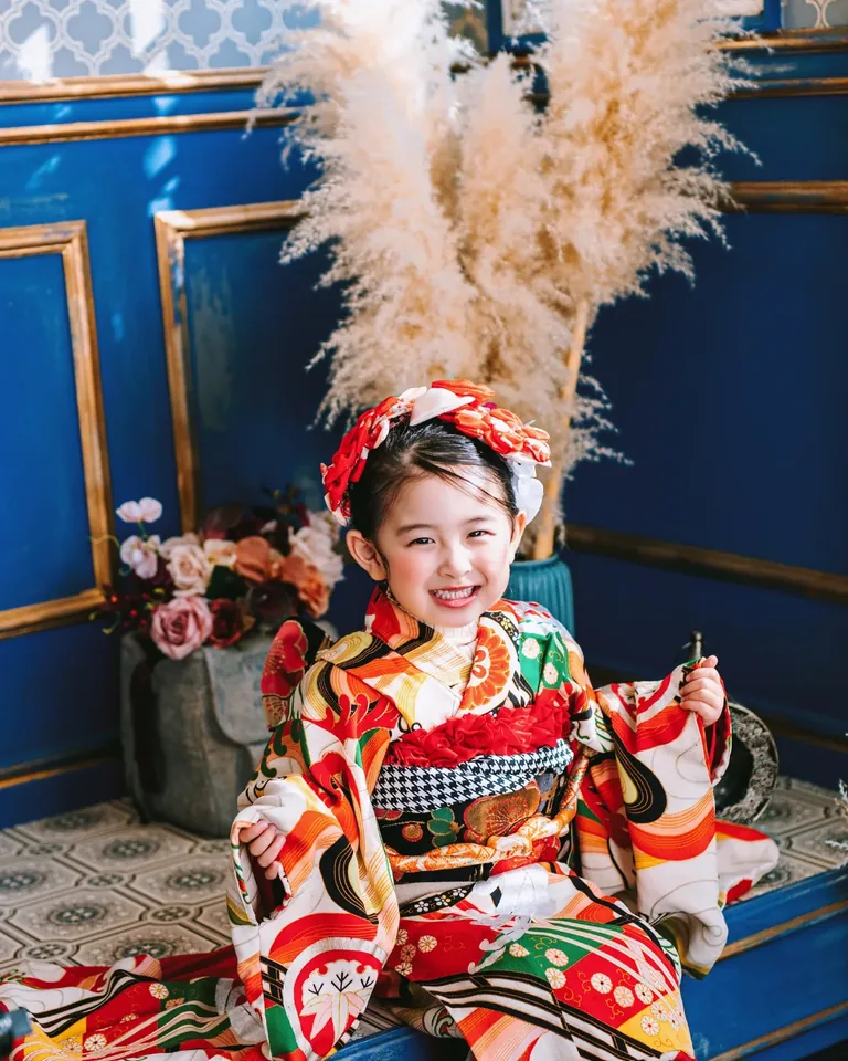 青いブティックで笑う、赤い着物の子ども