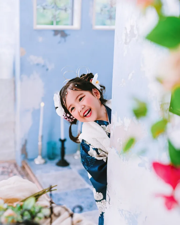 空色のアーチから顔をのぞかせる、和装の子ども